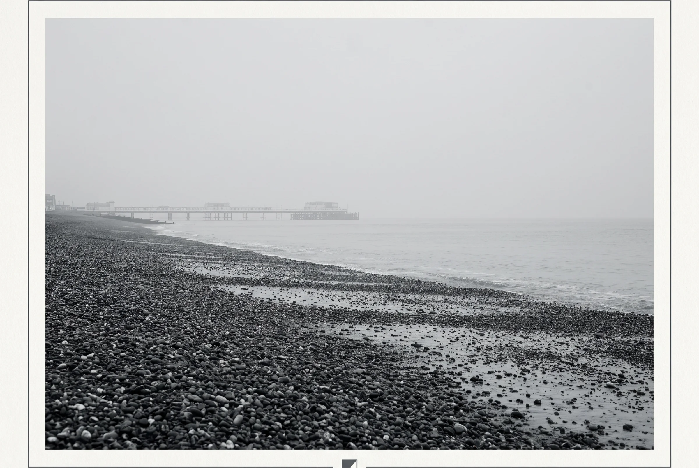 Worthing shingle beach and pier in coastal haze under an overcast sky